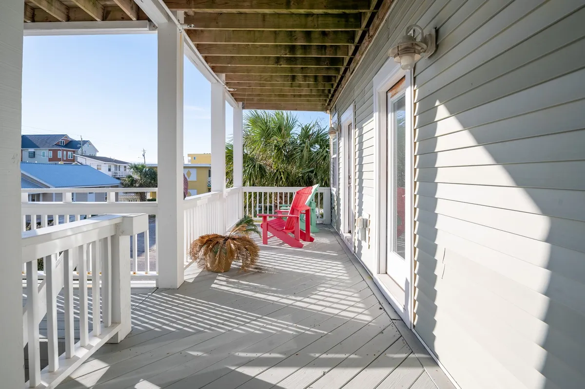 An inviting exterior scene with a red Adirondack chair and potted plant, set against a backdrop of palm trees. The area appears quiet and private, perfect for savoring morning coffee or unwinding after a day at the beach.