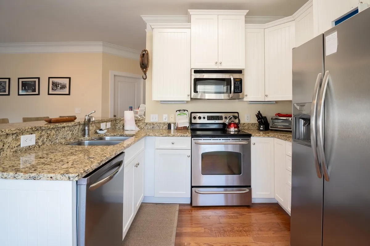A bright, well-equipped kitchen is showcased here, complete with granite countertops, stainless steel appliances, and white cabinetry. The space shines with natural light, emphasizing its functionality and modern design.