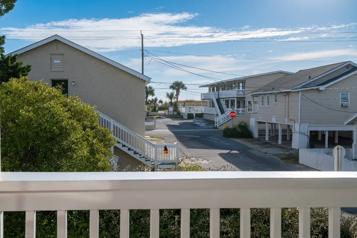 A relaxed neighborhood street view with palm trees, two nearby buildings, and a street sign under a clear sky. The scene suggests proximity to local attractions and the lively boardwalk area.
