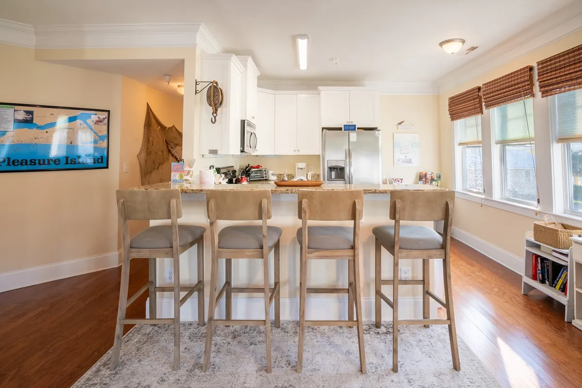 A bright, inviting kitchen with a central island and bar stools, a modern fridge, and colorful artwork on the walls. The space is set up for casual dining, meal prep, and socializing, reinforcing the condo's flexibility for guests to bring and use their own supplies.